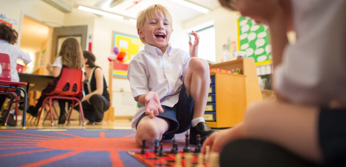 A BISNY Early Years child laughing during a game of chess